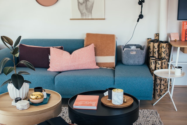 Living room with blue couch orange pillows and light wood coffee table